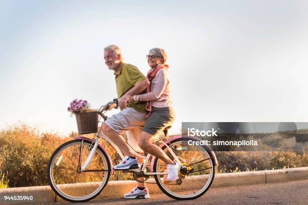 Senior Couple Move With A Bicycle Together Outdoor Like Children Stock Photo - Download Image Now
