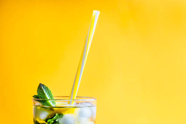 Ice tea with ice, lemon and mint on a combined colored yellow background. Summer cold drink cocktail. Copyspace