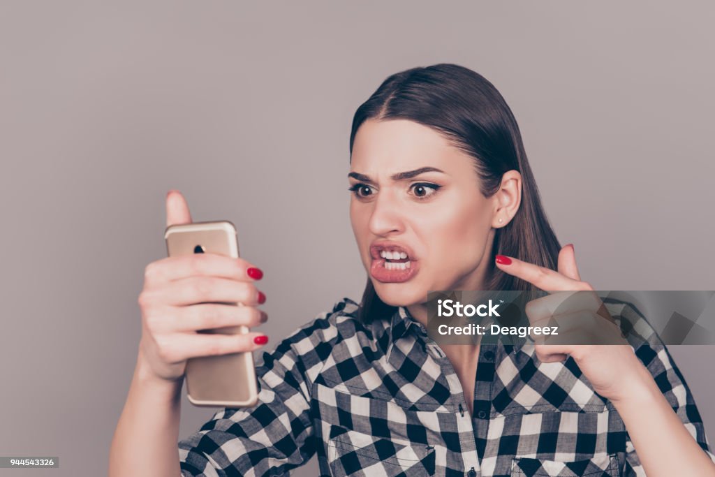 Young angry woman screaming at smartphone  while chatting with her boyfriend Anger Stock Photo