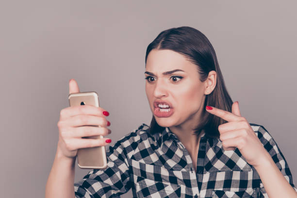 young angry woman screaming at smartphone  while chatting with her boyfriend - behavior women anger pointing imagens e fotografias de stock