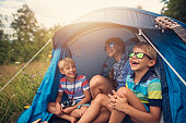 Kids having fun camping in tent on the forest meadow