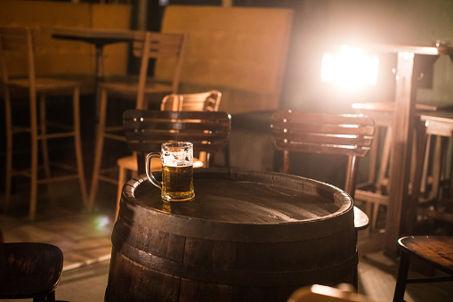Pint of beer on wooden barrel in pub