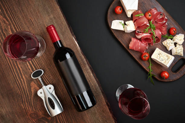 sopra vista aerea piatta giaceva natura morta di assortimento vari formaggi e gastronomia e vino rosso su una vecchia tavola di legno su tavolo nero - wine cheese food salami foto e immagini stock