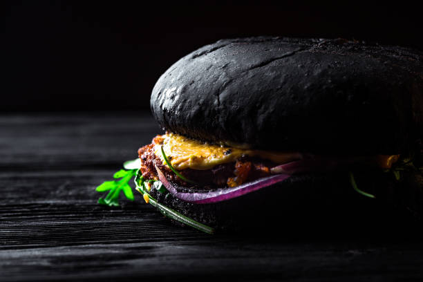 istock A large black burger with a beef, fried egg, onion and arugula on a black wooden table 944558708