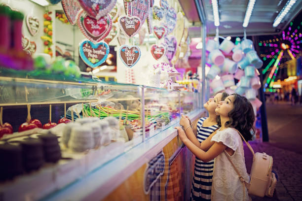 Two little girls are looking sweets in the candy wagon at the fun fair Two little girls are looking sweets in the candy wagon at the fun fair carnival children stock pictures, royalty-free photos & images