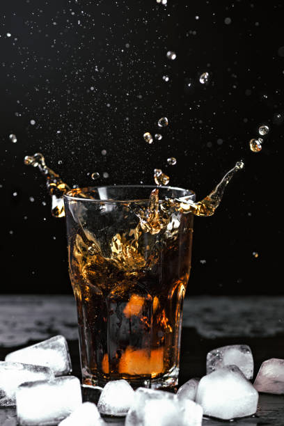 istock Cold drink in the glass with splashes and ice on a black background 944562100