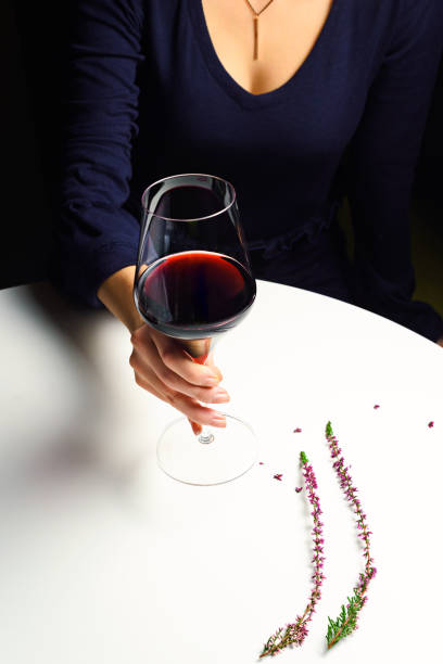 A woman is holding a glass of red wine in a cafe.