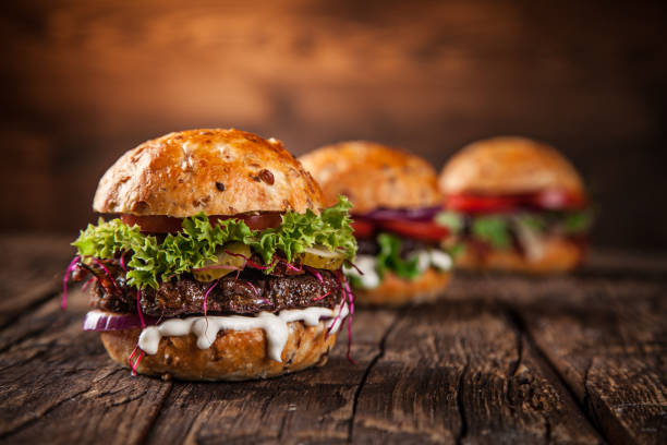 saborosos hambúrgueres na mesa de madeira - burger gourmet hamburger steak - fotografias e filmes do acervo