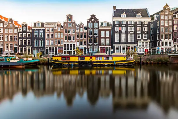 Long exposure shot of the Amsterdam Singel canal. Typical Amsterdam facades, and a yellow house boat complete the vibe that Amsterdam gives.