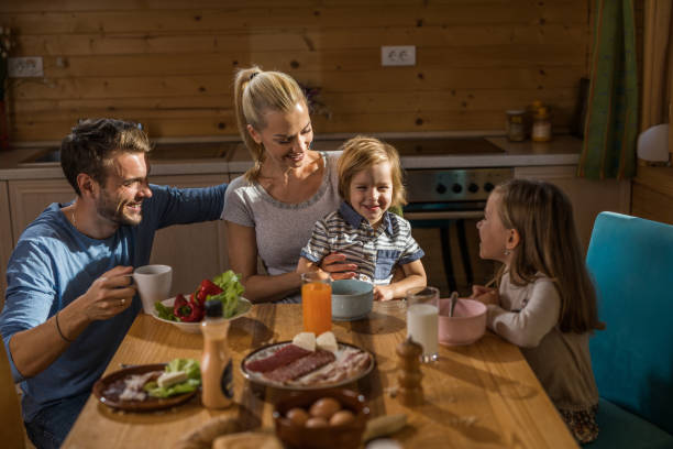 istock Young smiling parents and their small kids having a meal at dining table. 944573776