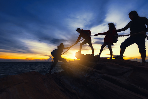 Young asian people climbing up on the mountain,hiking and team work concept.