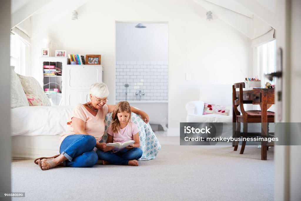 Grandmother and granddaughter reading a book in her bedroom Domestic Life Stock Photo