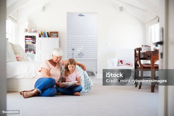 Grandmother And Granddaughter Reading A Book In Her Bedroom Stock Photo - Download Image Now