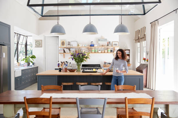 istock Mixed race woman leaning on kitchen island in open plan home 944580978