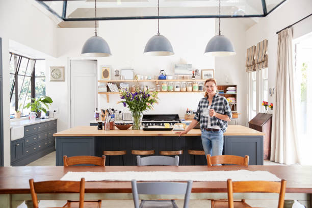 istock Woman leaning on island in an open plan kitchen dining room 944580988