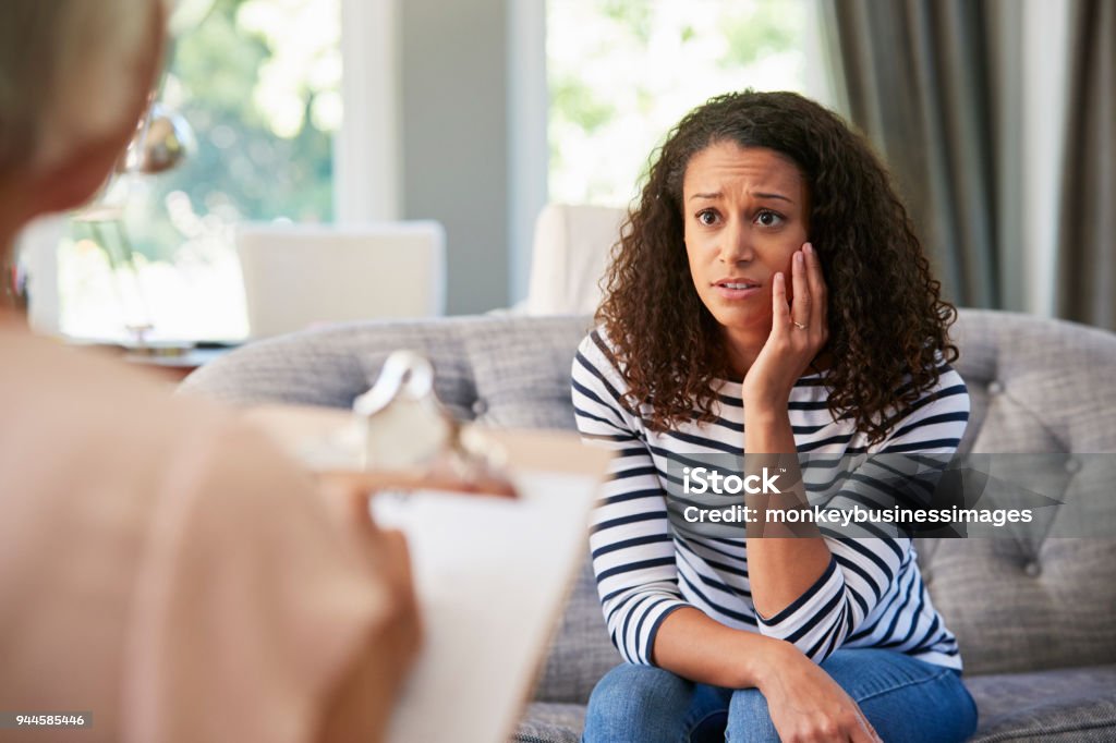 Depressed young woman having therapy with a psychologist Psychotherapy Stock Photo