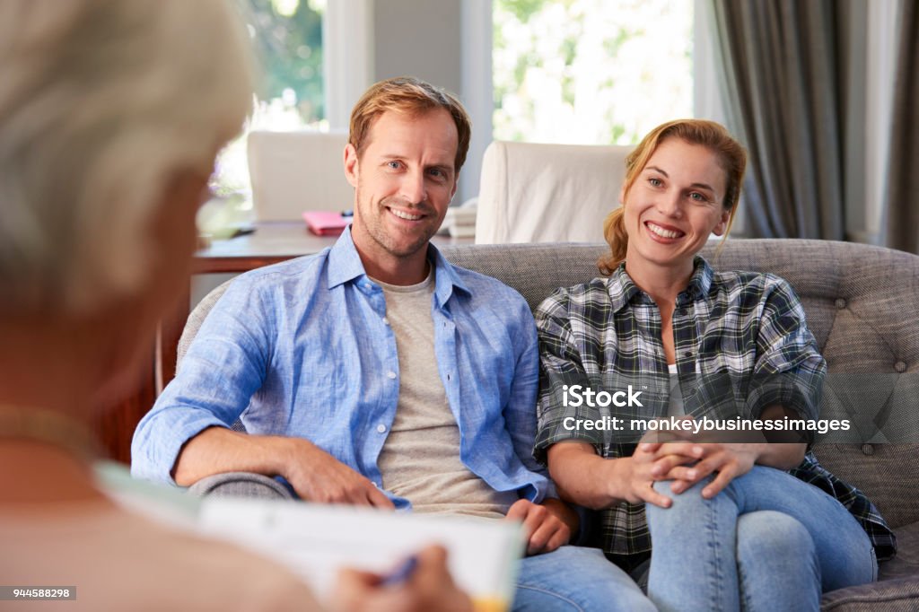 Heureux jeune couple prenant conseils financiers à la maison - Photo de Séance de psychothérapie libre de droits