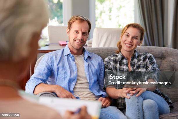 Happy Young Couple Taking Financial Advice At Home Stock Photo - Download Image Now - Psychotherapy, Couple - Relationship, Blond Hair