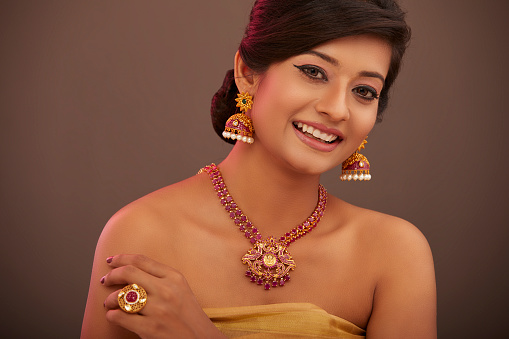 Cheerful Indian attractive young women with traditional red stone jewelry in studio shot.