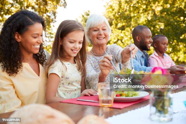 Photo libre de droit de Famille Et Amis En Train De Déjeuner Autour Dune Table Dans Le Jardin banque d'images et plus d'images libres de droit de Famille multi-générations