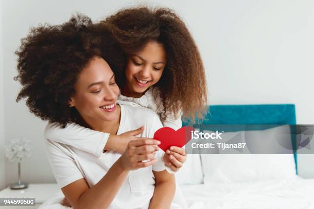 Mother And Daughter Enjoying On The Bed Holding A Heart Stock Photo - Download Image Now