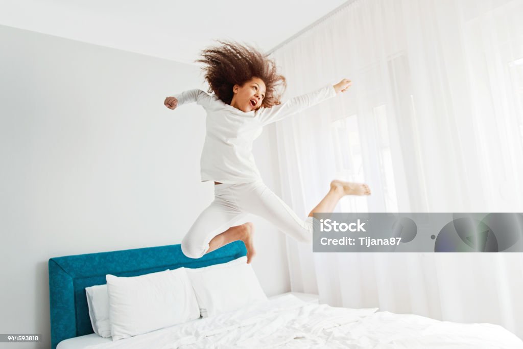 Cute girl jumping on the bed, happiness, joyful Jumping Stock Photo