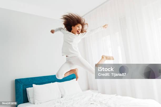 Cute Girl Jumping On The Bed Happiness Joyful Stock Photo - Download Image Now - Jumping, Bed - Furniture, Child