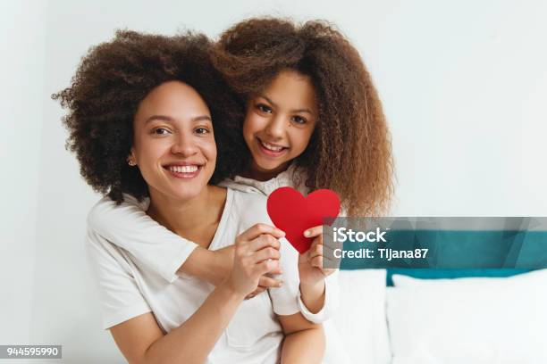 Mother And Daughter Enjoying On The Bed Holding A Heart Stock Photo - Download Image Now