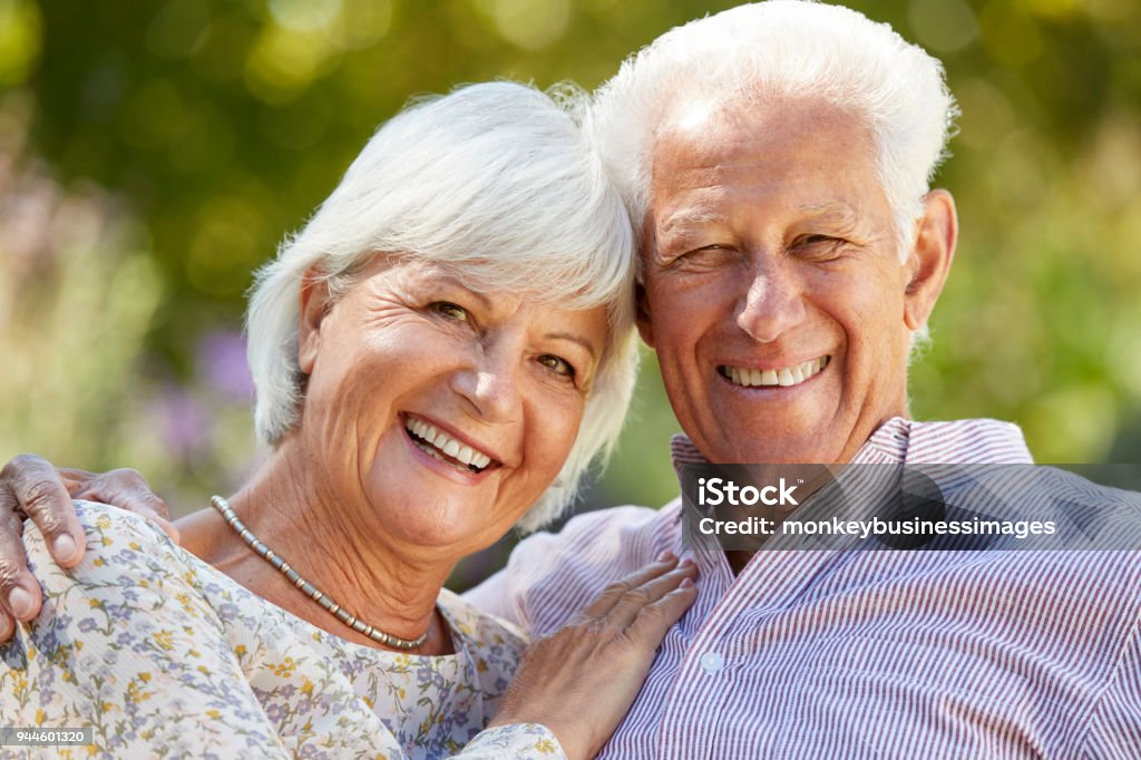Feliz pareja senior abrazando en jardín, cabeza y hombros - Foto de stock de 60-69 años libre de derechos