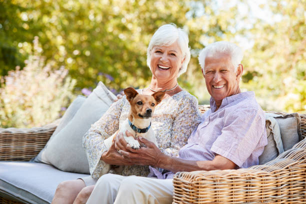 felice coppia senior seduta con un cane da compagnia in giardino - necklace horizontal waist up outdoors foto e immagini stock