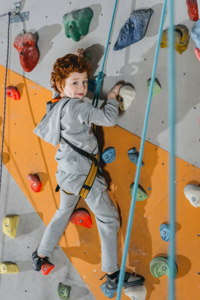 istock Little boy climbing wall with grips 944605130