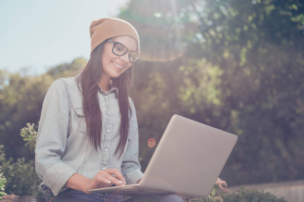 istock Pretty smiling hipster girl relaxing in the park and using tablet 944606290