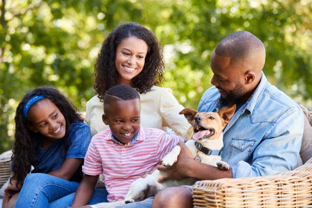 Parents and two kids sitting with pet dog in the garden Parents and two kids sitting with pet dog in the garden pet owner photos stock pictures, royalty-free photos & images
