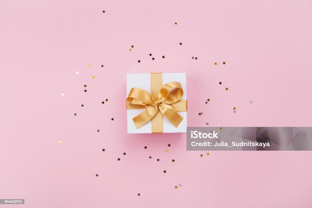 Gift or present box and stars confetti on pink pastel table top view. Flat lay composition for birthday, mother day or wedding. Gift or present box and stars confetti on pink pastel table top view. Flat lay composition for birthday, mother day or wedding. Copy space for text. Gift Stock Photo