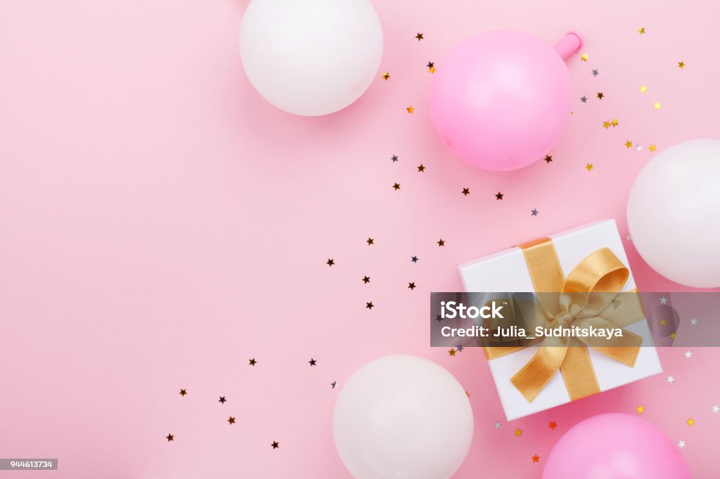 Gift or present box, balloons and confetti on pink table top view. Flat lay for birthday, mother day or wedding. Gift or present box, balloons and confetti on pink table top view. Flat lay composition for birthday, mother day or wedding. Gift Stock Photo