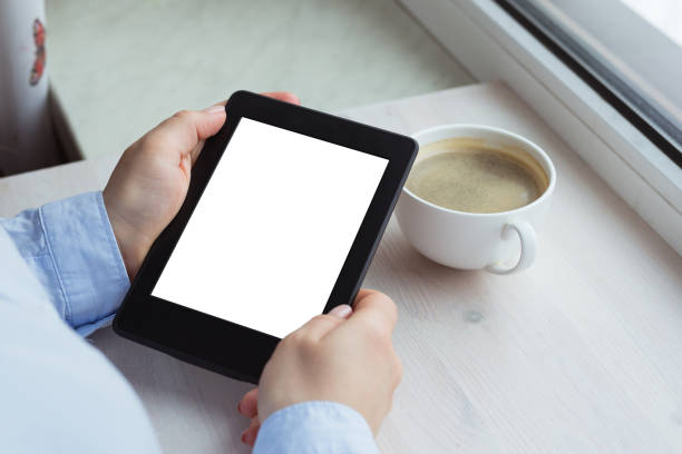 istock Young woman sitting by the window with an e-book 944613748