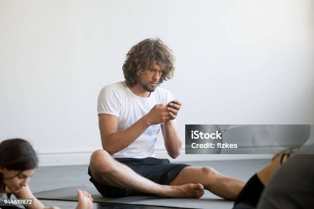 Young Man Sitting Texting A Message Using His Mobile Phone Stock Photo - Download Image Now