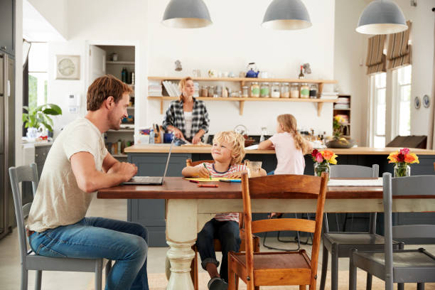 istock Dad and son at kitchen table, mum and daughter in background 944620314