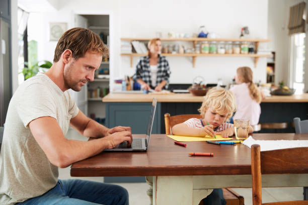 istock Dad and son at kitchen table, mum and daughter in background 944620316