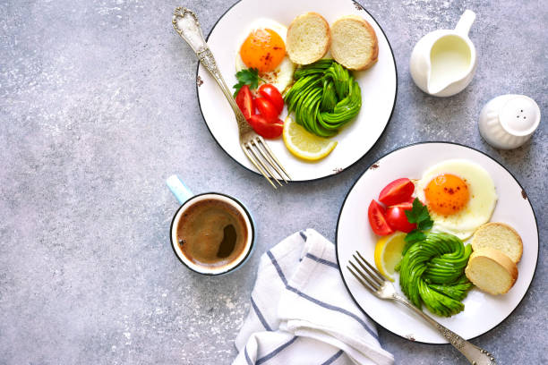 istock Two breakfast plates with fried egg, avocado rose and baguette 944626590