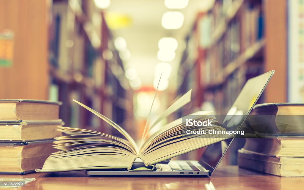 Libro y la tecnología informática en biblioteca - Foto de stock de Profesor libre de derechos