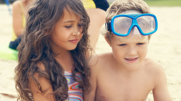 portret dzieci na plaży w lecie. mała dziewczynka siedząca z er frend na piasku i uśmiechnięta - frend zdjęcia i obrazy z banku zdjęć