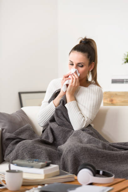 istock Woman in cold and flu sneezing nose with tissue 944634444
