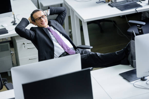 istock smiling businessman with hands behind head resting at workplace 944637434