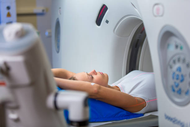 Pretty, young woman goiing through a Computerized Axial Tomography (CAT) Scan medical test/examination in a modern hospital (color toned image; shallow DOF)