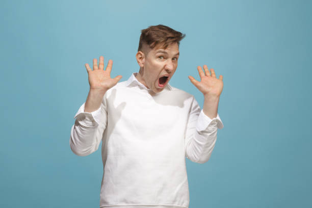 istock The young emotional angry man screaming on blue studio background 944642608