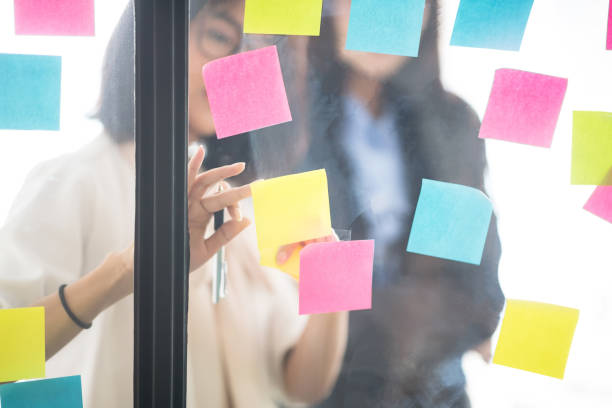 istock Businesspeople putting their ideas at sticky notes on window. 944643596