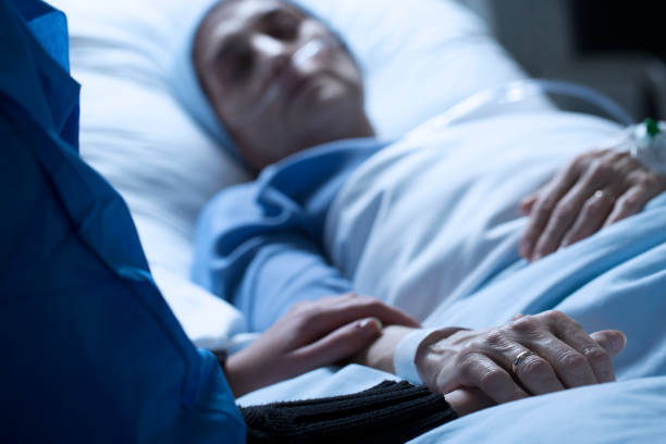 Saying goodbye to dying mother Young woman holding hands and saying goodbye to her dying of cancer mother in hospice sick woman hospital bed stock pictures, royalty-free photos & images
