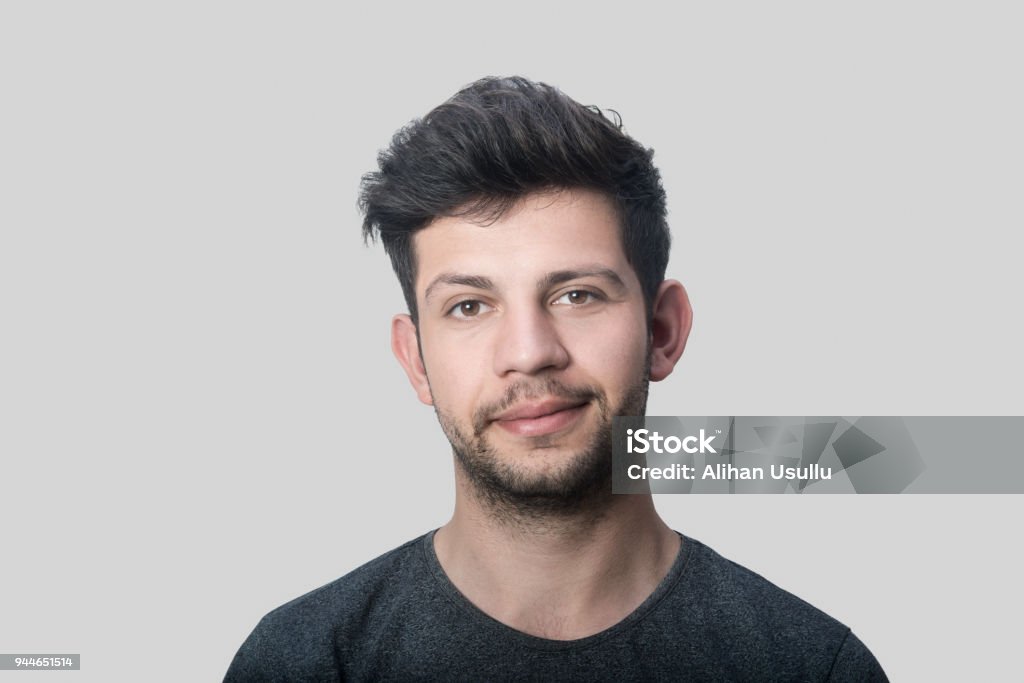 Portrait of smiling young man looking at camera over gray background Portrait of smiling young man looking at camera over gray background. Horizontal composition. Studio shot. Men Stock Photo