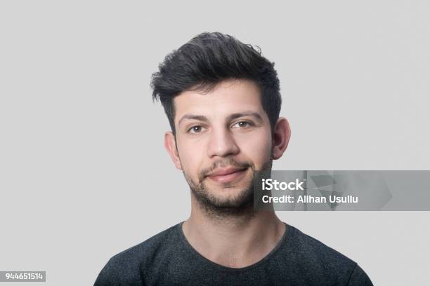 Portrait Of Smiling Young Man Looking At Camera Over Gray Background Stock Photo - Download Image Now